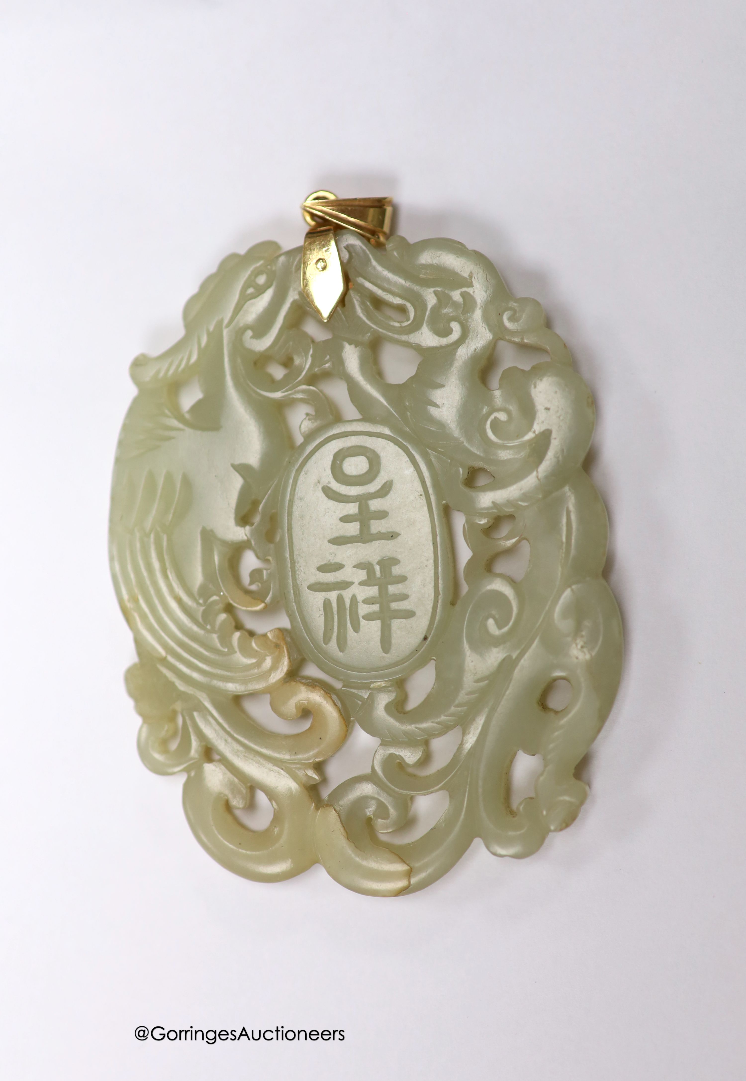 A Chinese yellow metal amounted jade pendant, 63mm, carved with dragons and character marks.